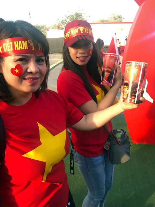 Две вьетнамские девушки держат пластиковые сувенирные стаканчики Coca-Cola на Кубке Азии по футболу 2019 года