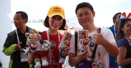 Football fans hold cups of Coca-Cola with their photos at the 2018 football championship
