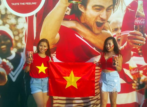 Две девушки с флагом Вьетнама держат именные стаканы Coca-Cola на Кубке Азии по футболу 2019 года